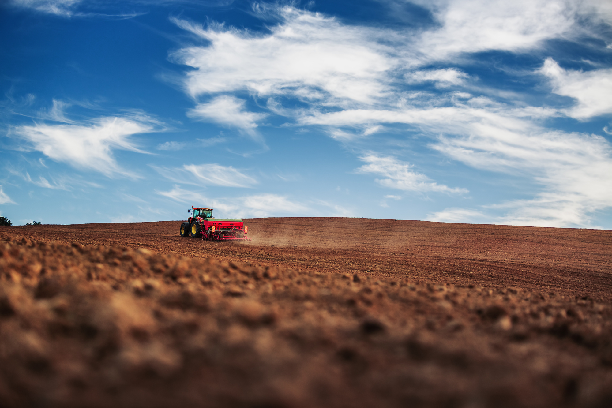 Farmer with tractor seeding crops at field