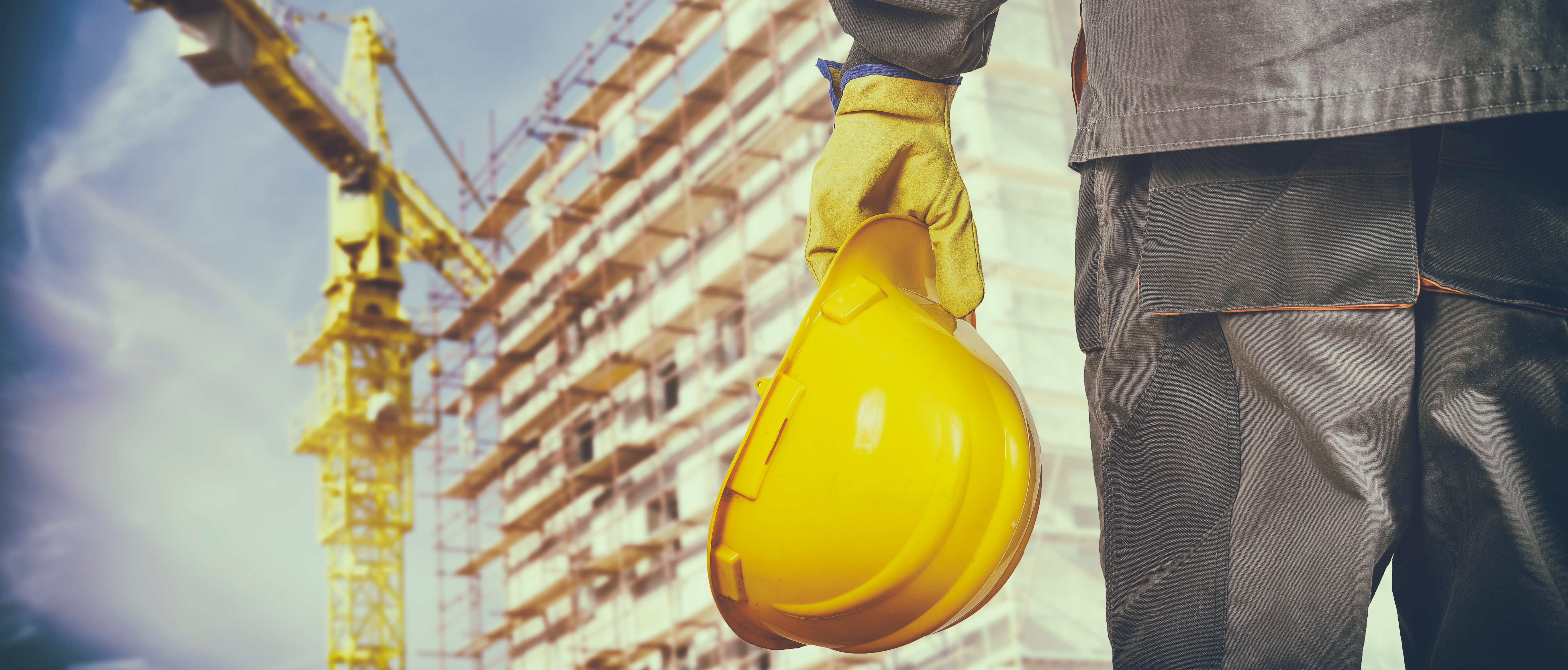 worker with protective uniform in front of construction scaffold